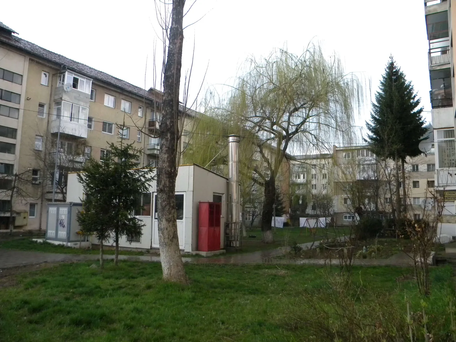 Clădirea unei centrale termice de cartier, cu un coș metalic scurt, între blocuri de locuințe