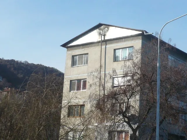 Bloc de locuințe mansardat, cu un coș de fum metalic pe fațadă