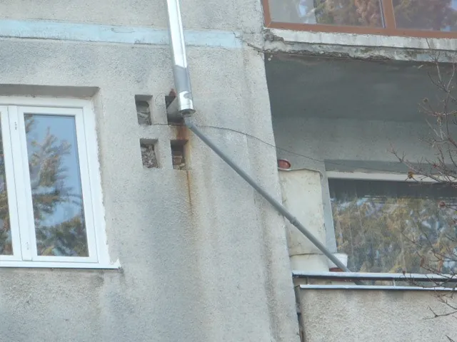 Coș de fum pe fațadă, din care pleacă un tub de plastic care duce condensul spre un balcon