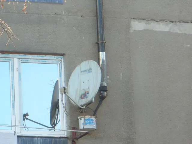 Găleată pentru condens agățată de antena parabolică, sub un coș de fum