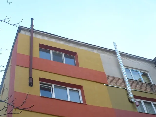 Două apartamente reabilitate termic la penultimul etaj: în stânga un coș de fum ruginit, neizolat, în dreapta un coș izolat cu folie argintie