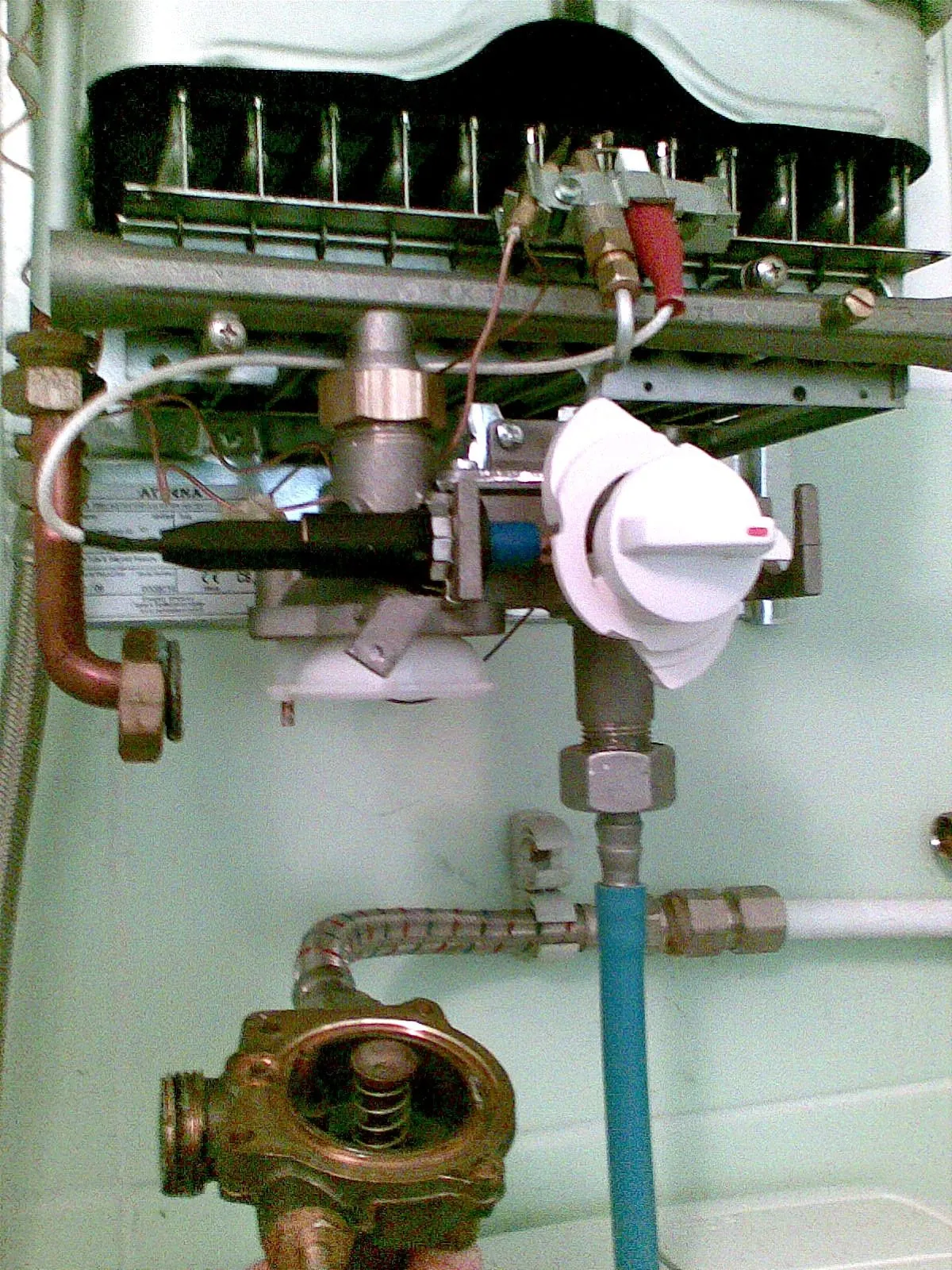 Încălzitor instantaneu de apă pe gaz fără carcasă, cu arzătorul și racordurile vizibile