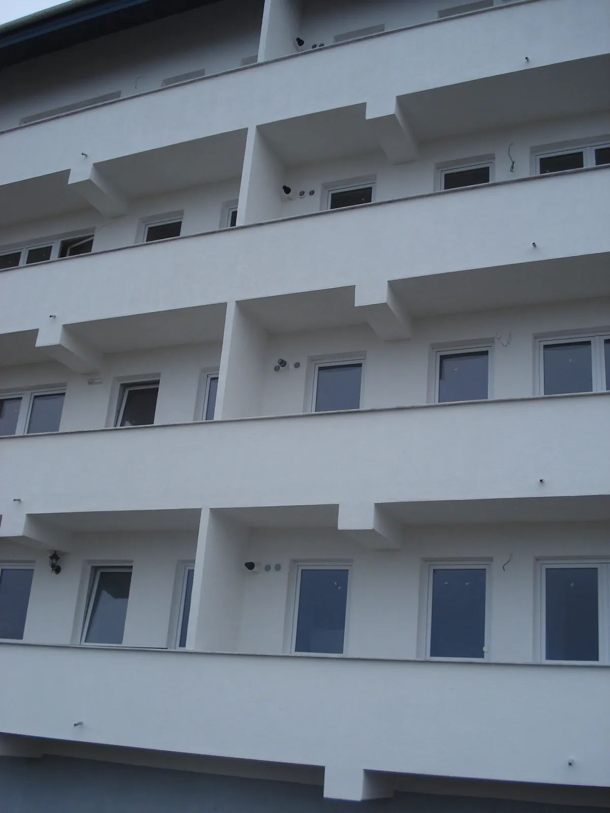 Fațadă de bloc nou cu balcoane suprapuse, sub care ies terminalele centralelor termice murale
