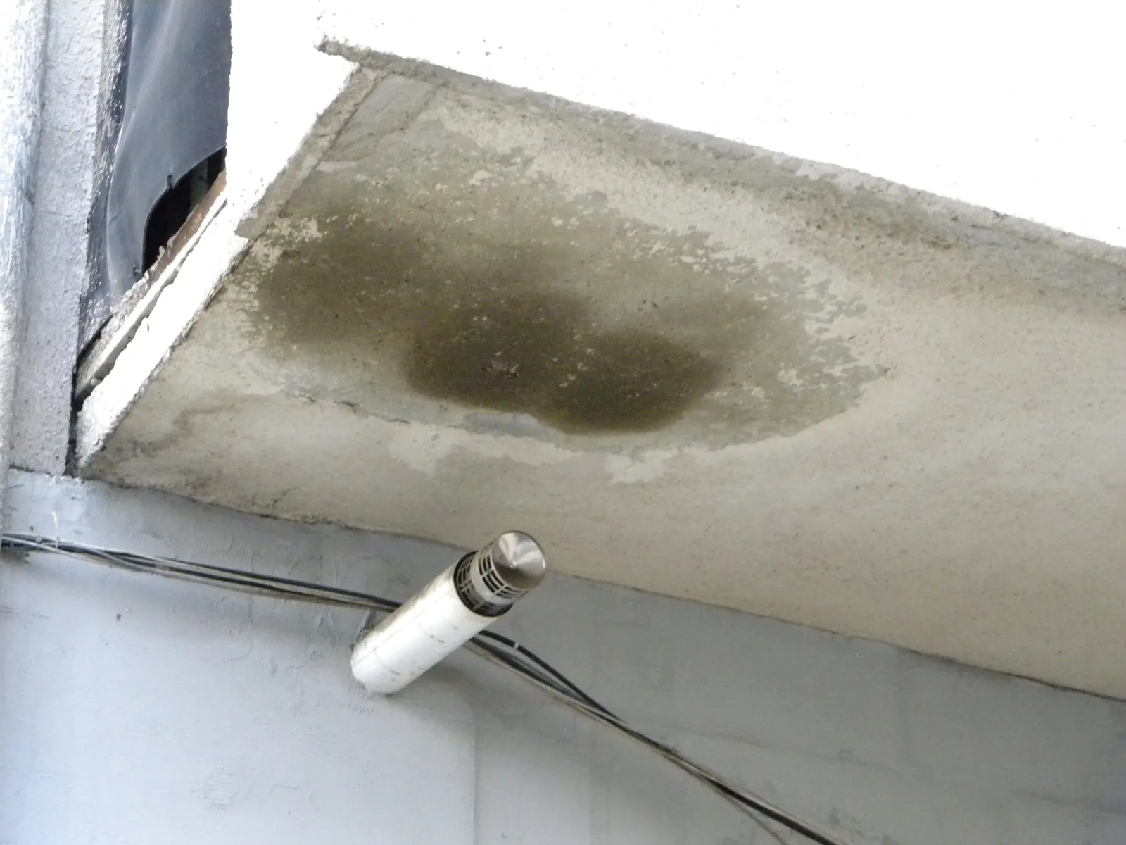 Terminal concentric sub un balcon, cu o pată întunecată de condens pe placa balconului de deasupra