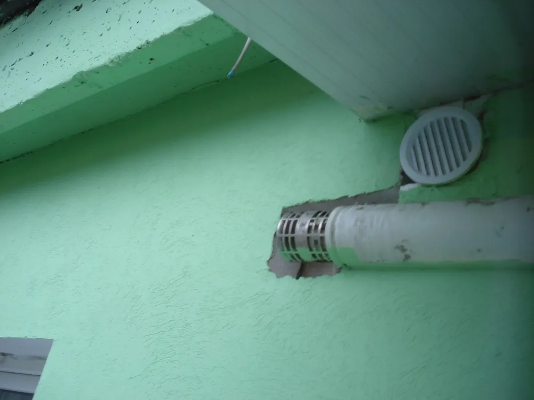 Terminal de evacuare îngropat în termoizolație, lipit de perete, sub grila unui orificiu de ventilare